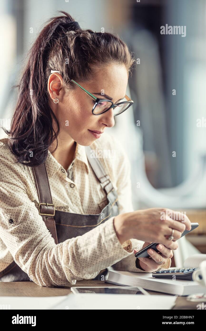 Beautiful business owner works with a calculator to do bookkeeping wearing glasses. Stock Photo