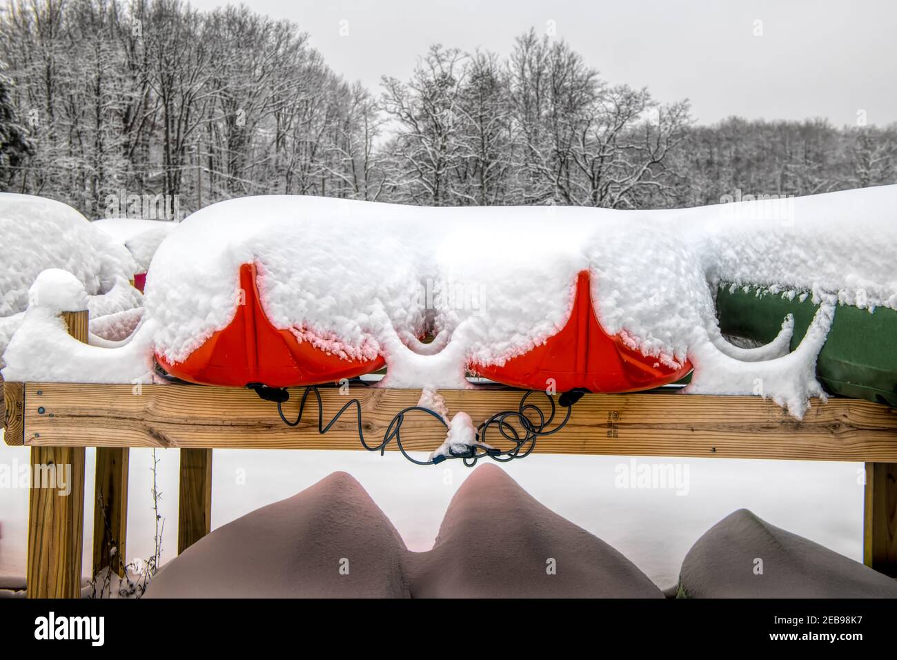 Closeup shot of kanu boats covered in snow near a forest in winter Stock Photo
