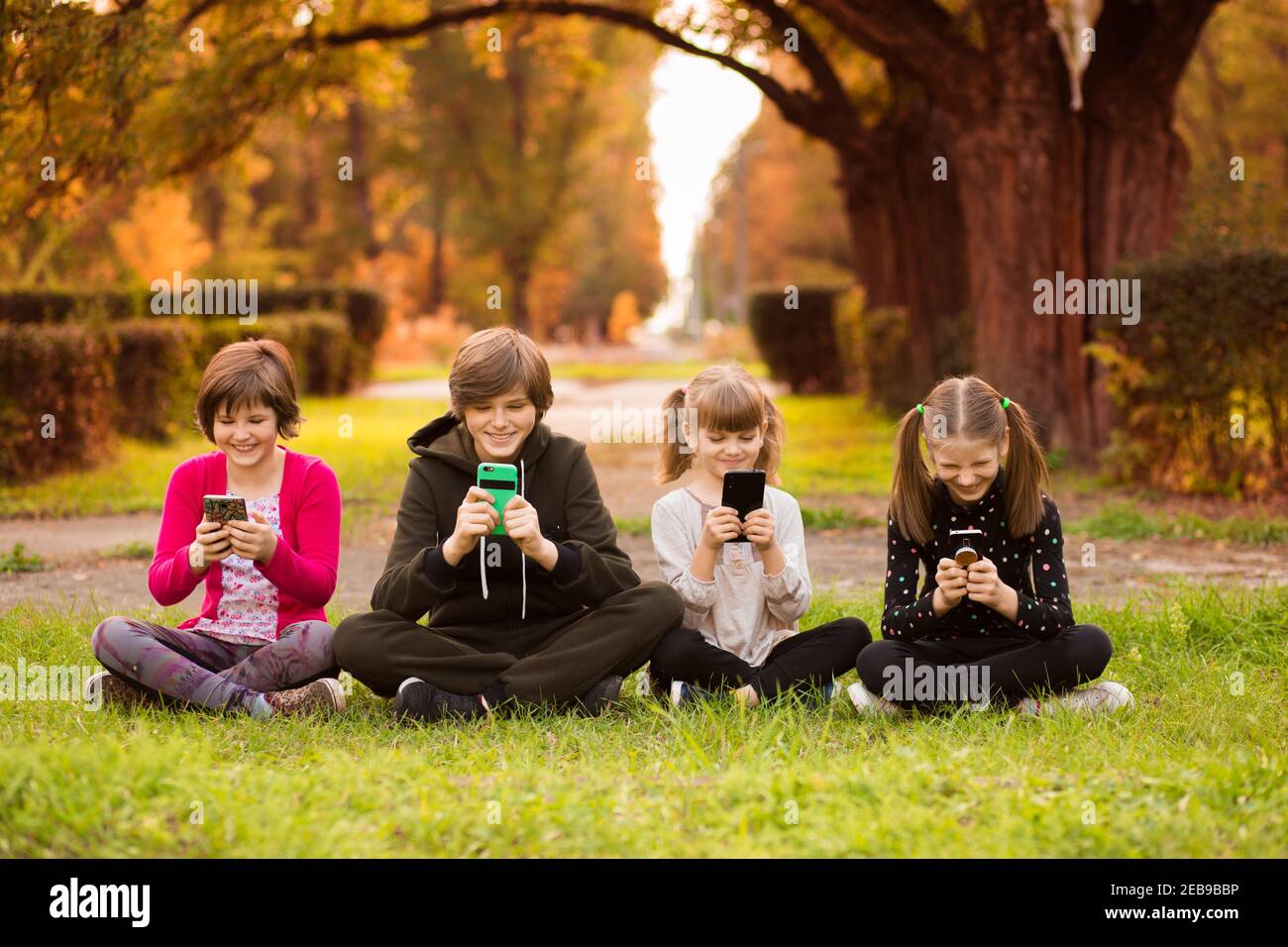 Smartphone addiction group of little children watching film movie cartoon together on digital tablet. Kids playing with phone together Stock Photo