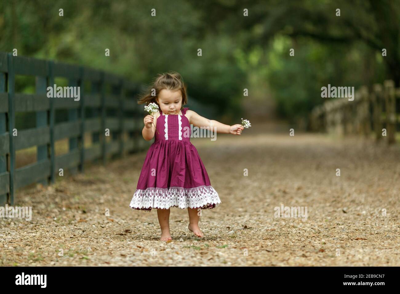 Beautiful two year old girl with a purple dress running and jumping with happiness. Stock Photo