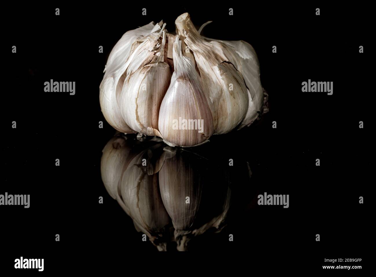 Cloves of garlic and its reflection on a dark background Stock Photo ...