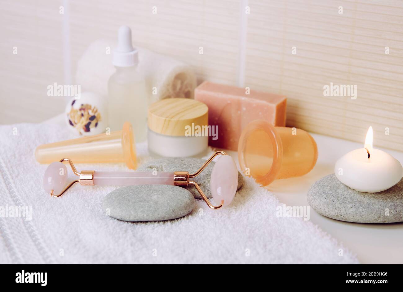 Cozy home spa and self care concept. Various spa tools in home bathroom: rose quartz face rolling tool, facial and body silicone cupping tools. Stock Photo