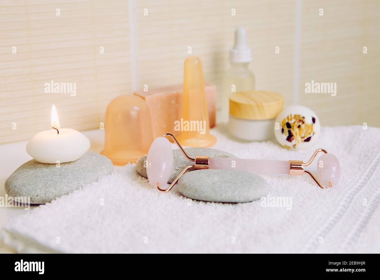 Cozy home spa and self care concept. Various spa tools in home bathroom: rose quartz face rolling tool, facial and body silicone cupping tools. Stock Photo