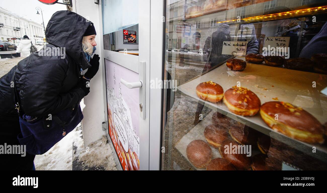 Warsaw, Poland. 11th Feb, 2021. A woman orders Polish fried donuts, or Paczki, at a bakery in Warsaw, Poland, Feb. 11, 2021. People in Poland eat Paczki, fried donuts filled with cream or jam, on Fat Thursday to mark the last Thursday before the start of Lent. Credit: Jaap Arriens/Xinhua/Alamy Live News Stock Photo