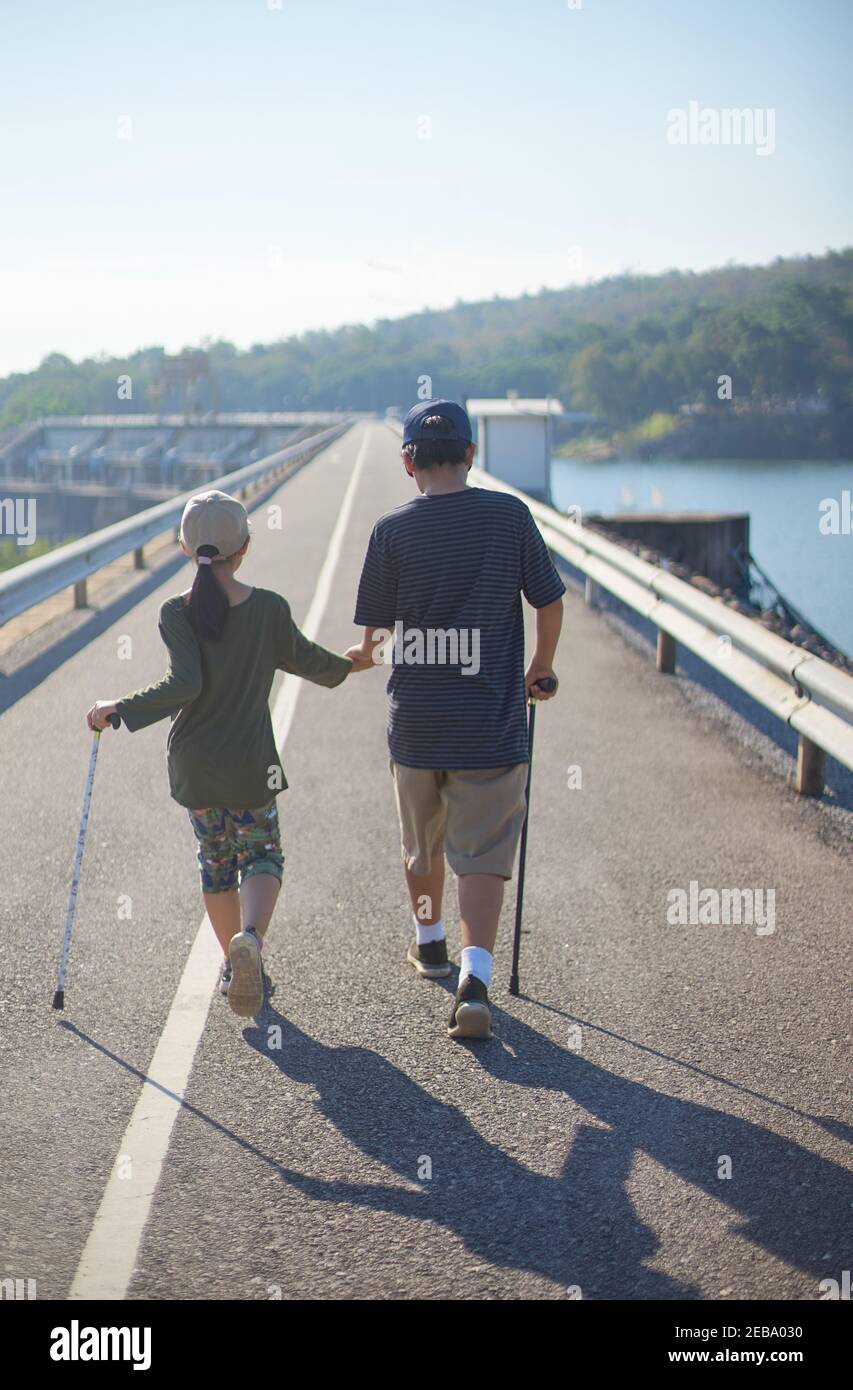 Brother and sister walking together on the asphalt road Stock Photo - Alamy