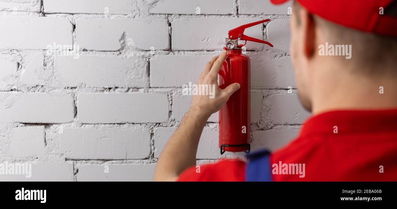 safety equipment servicing and maintenance - service worker checking fire extinguisher condition. copy space Stock Photo