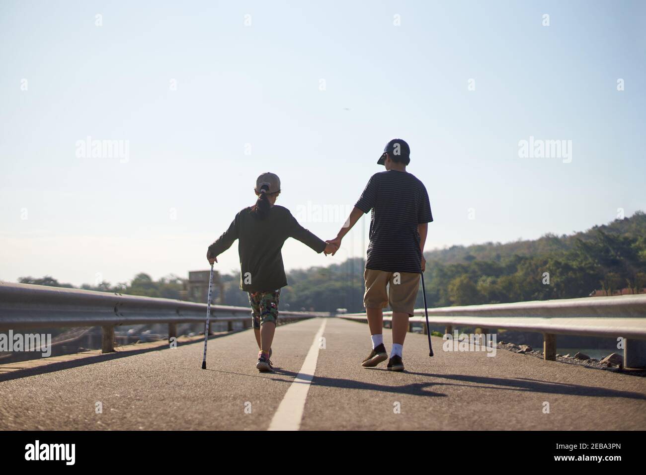 Brother and sister walking together on the asphalt road Stock Photo - Alamy