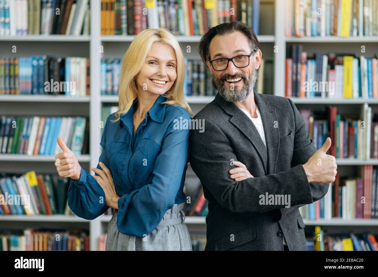 Successful happy business people in formal wear at the workplace. Mature confident male and female colleagues look directly at the camera, smiling, teamwork concept Stock Photo