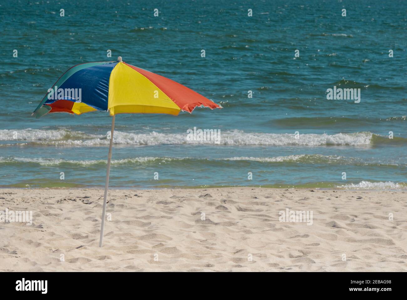 Bright colors umbrella sunny day on coast and wavy sea background