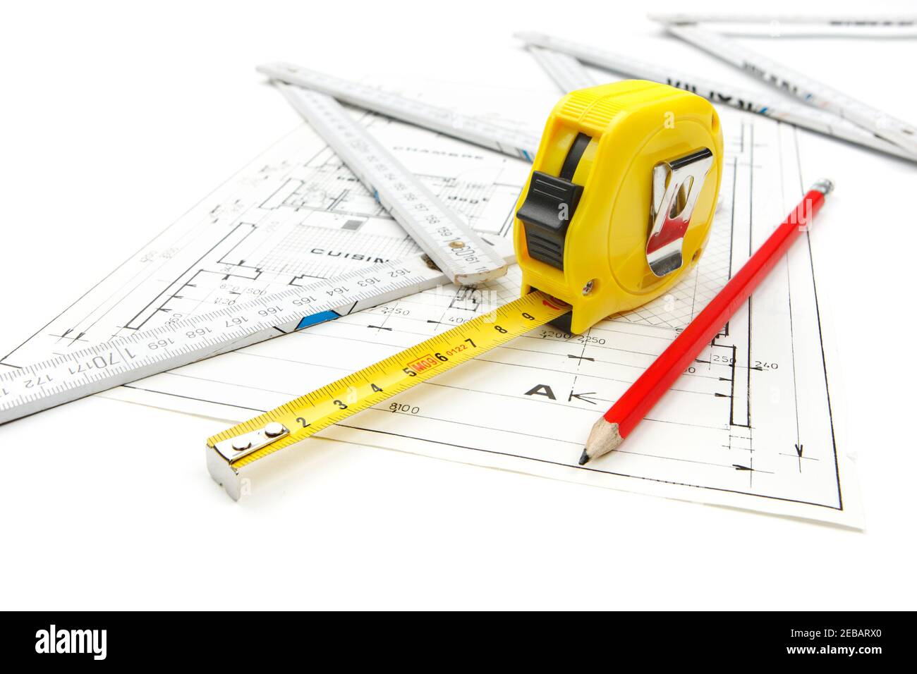 Work tools equipment arranged on house construction plans with tape measure, pencil and wooden ruler. Shooting studio photo isolated on white backgrou Stock Photo