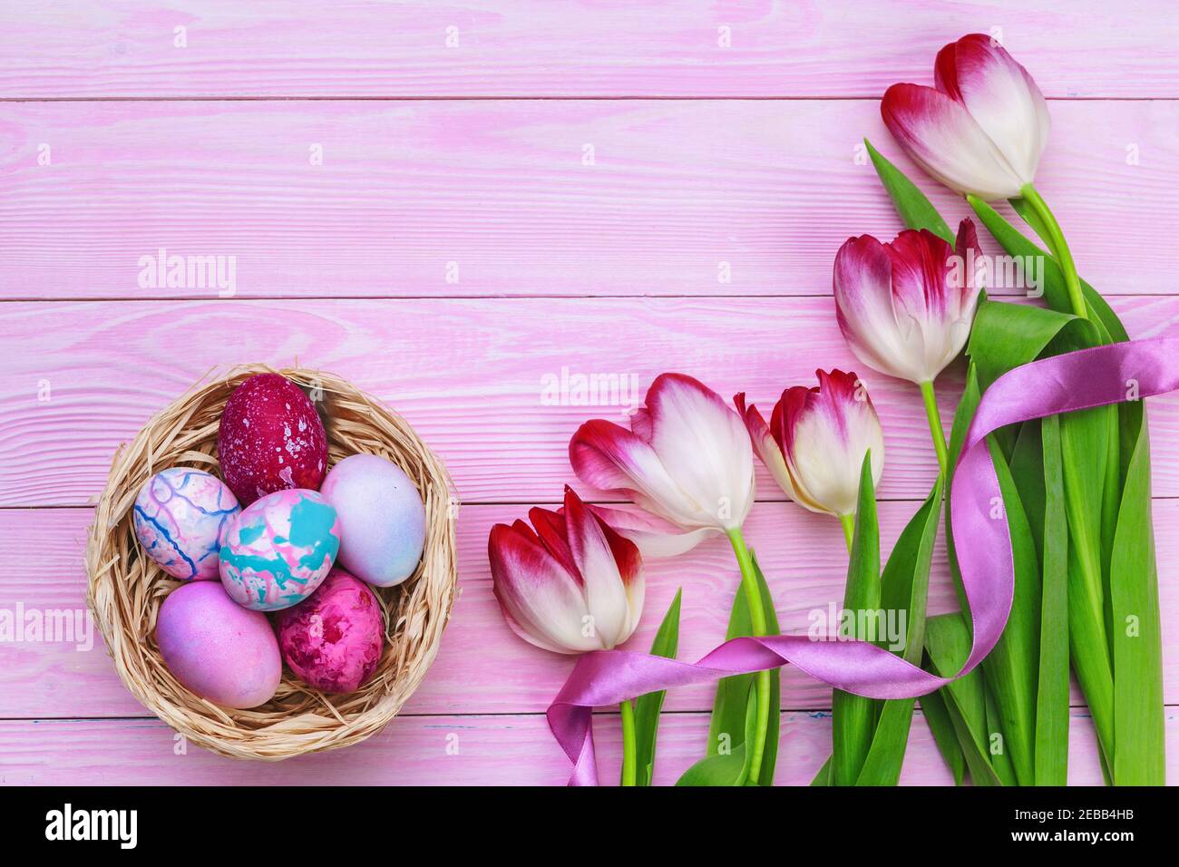 Easter background with colorful eggs and tulips over pink wood. Top ...