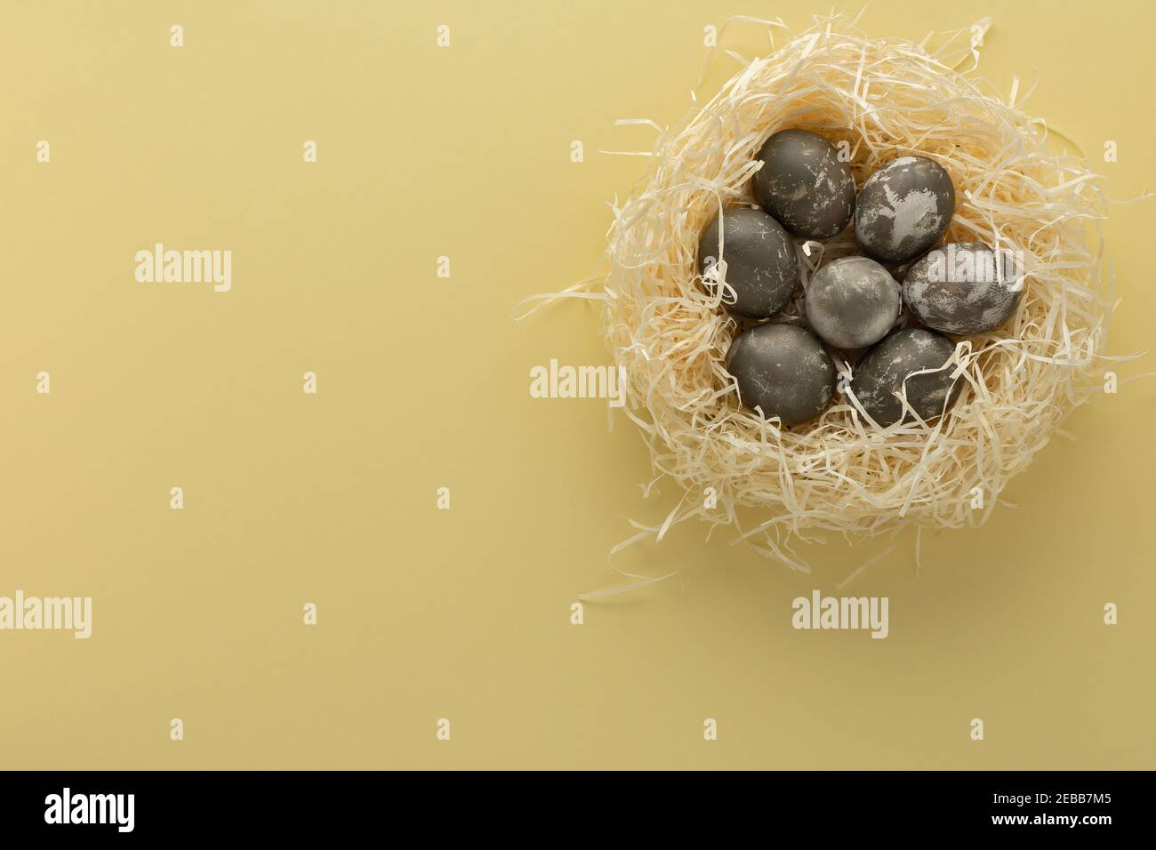 Silver easter eggs in straw nest, easter nest isolated on yellow background Stock Photo