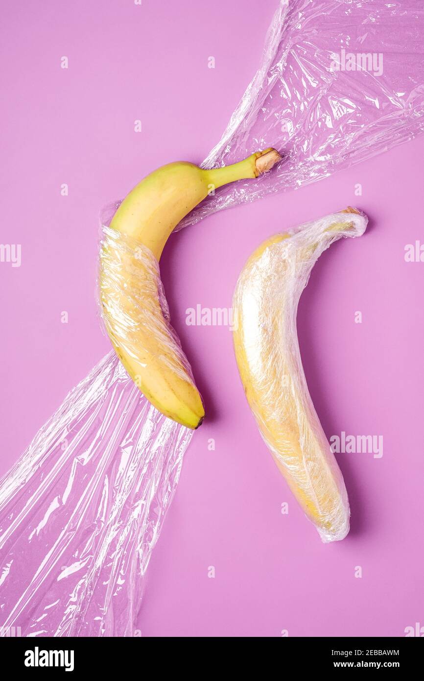 Banana fruit wrapped in stretch plastic on pink background Stock Photo