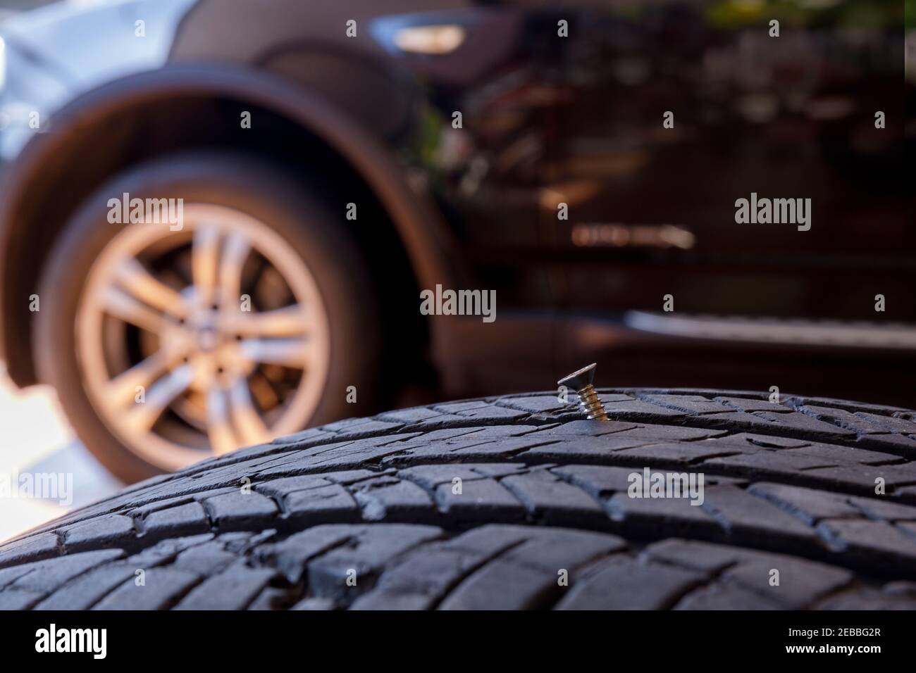 Close up old tire have nails nut or screw drive stuck in side. Tire