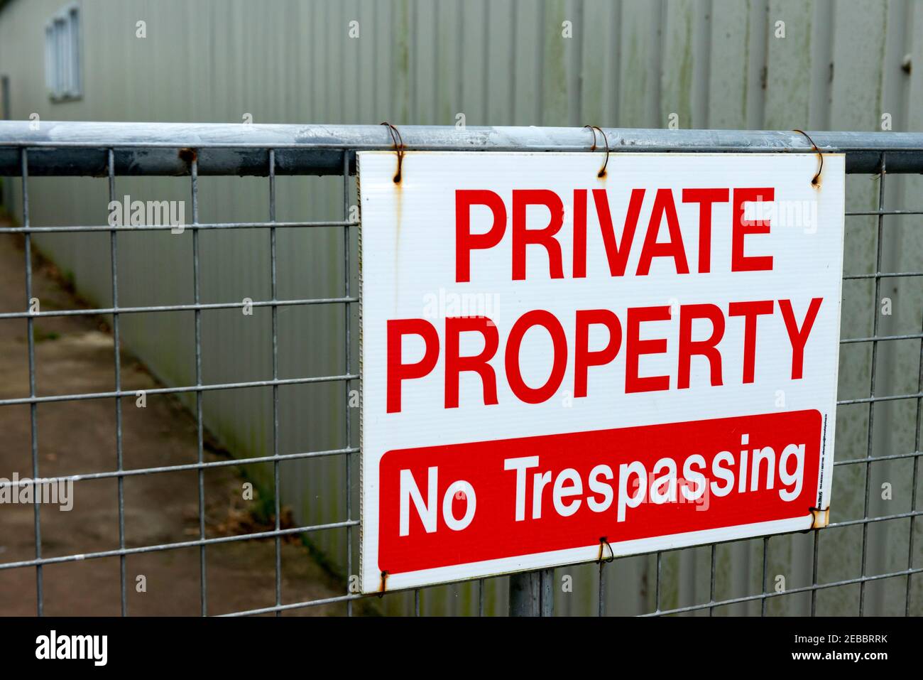 Private Property No Trespassing red warning sign on backyard fence of commercial business building Stock Photo