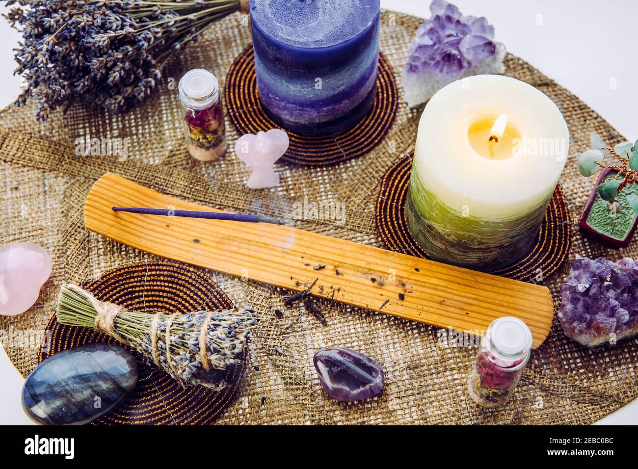 Small good feng shui altar in home on window sill on leaf shape table mat, snowy Nordic nature on background. Incense candle smoking, gemstones for de Stock Photo