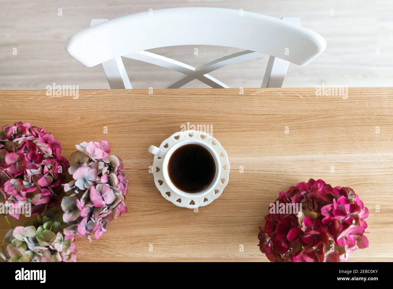 Coffee in white cup on the table among flowers of hydrangea Stock Photo