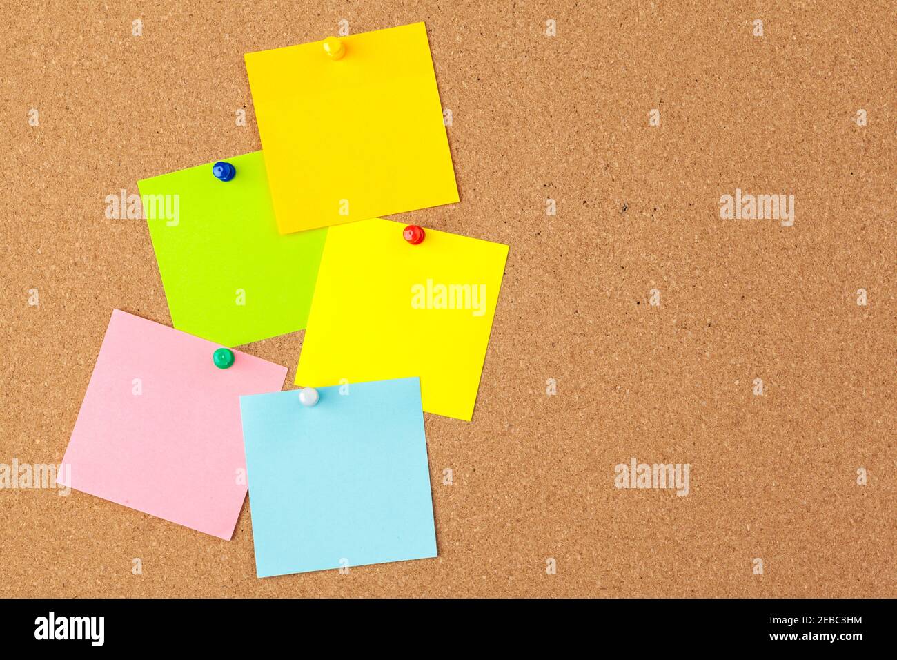 Cork board with several colorful blank notes with pins Stock Photo