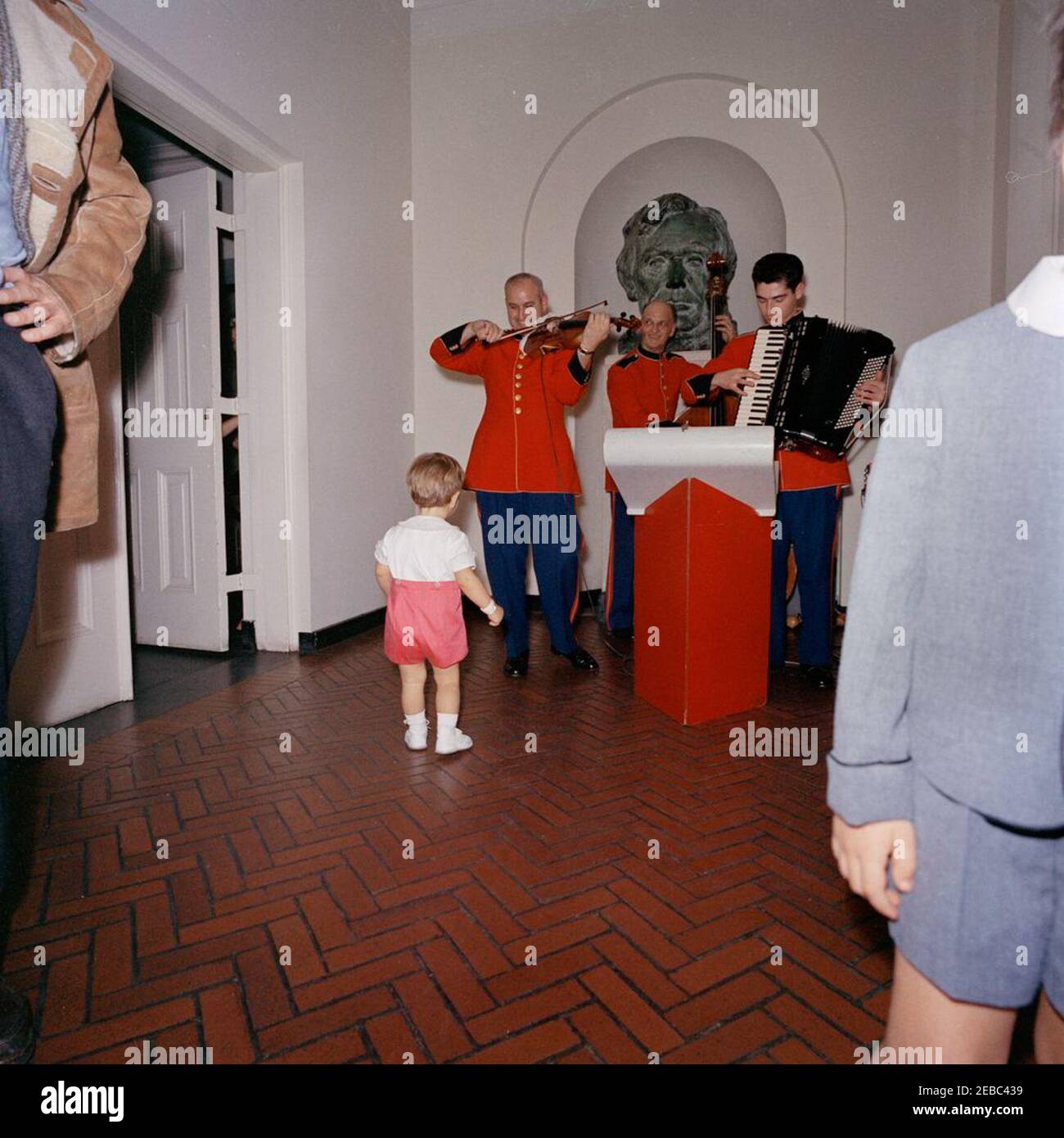 Birthday party for Caroline Kennedy and John F. Kennedy, Jr.. John F.  Kennedy, Jr. (back to camera), watches members of the United States Marine  Band, including accordionist Sergeant Major Charles Vincent Corrado