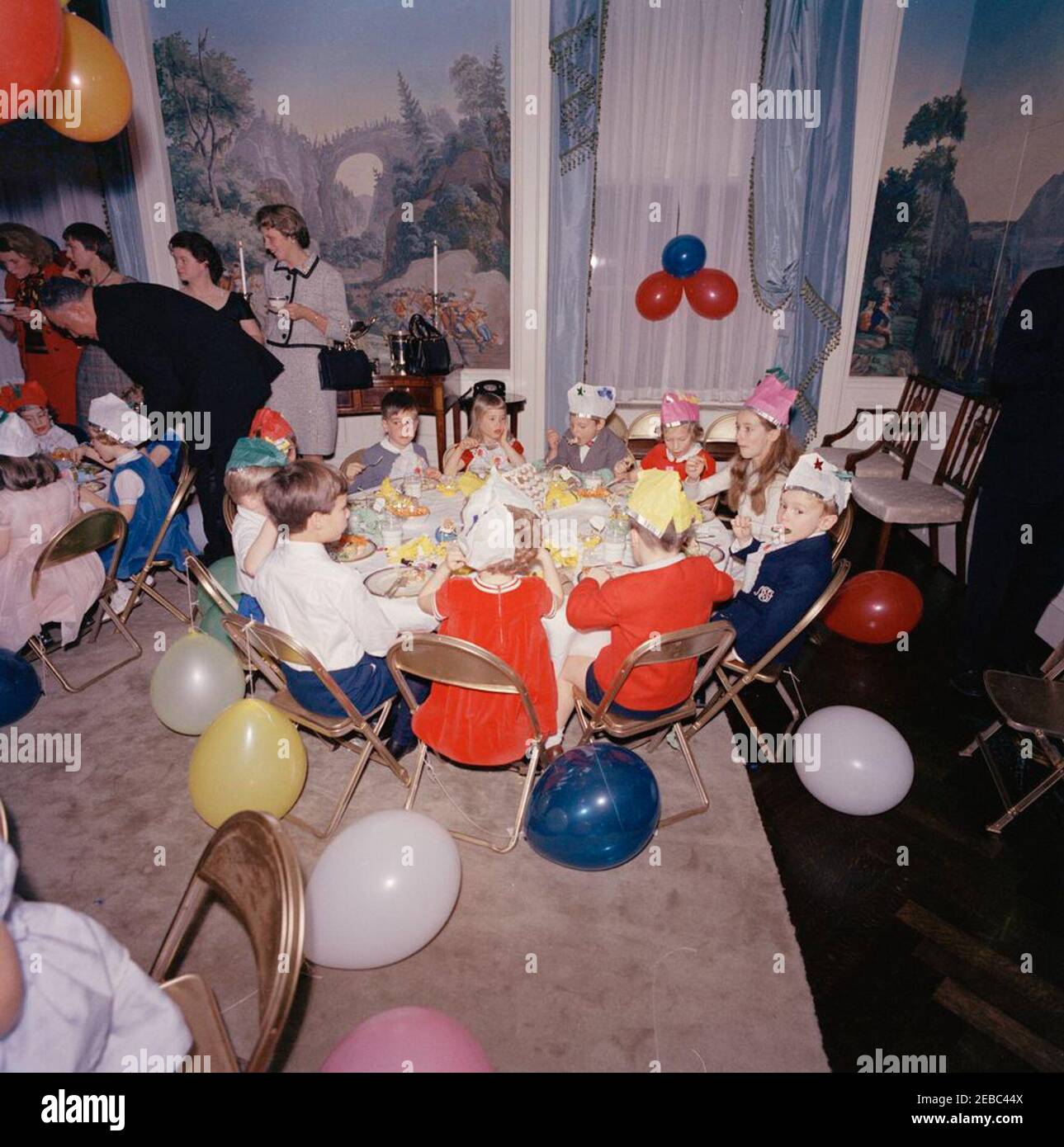 Birthday party for Caroline Kennedy and John F. Kennedy, Jr.. Young children eat at a table in the Presidentu2019s Dining Room (Residence) of the White House, Washington, D.C., during a joint birthday party for Caroline Kennedy and John F. Kennedy, Jr.; White House butler, John W. Ficklin (leaning down), stands at left. Stock Photo