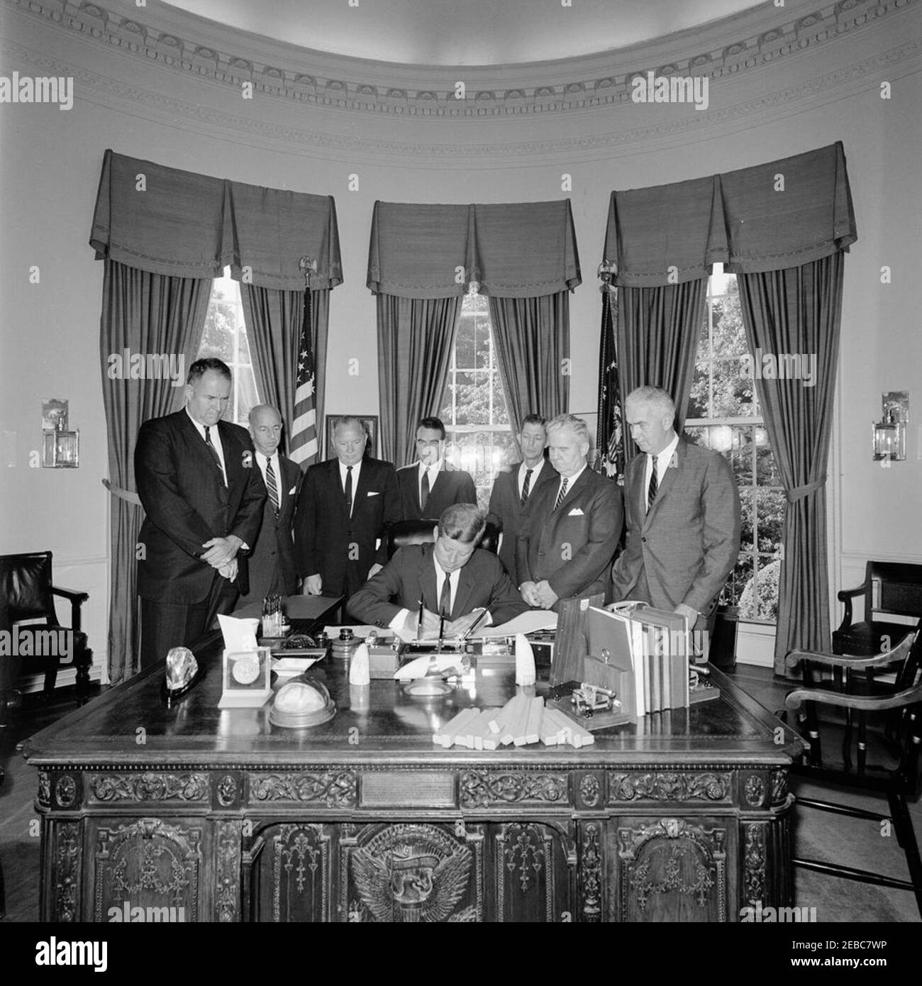 Bill signing - House Joint Resolution 783 Public Law 87-678, Delaware-New Jersey Compact, 9:50AM. President John F. Kennedy (seated at desk) signs the Delaware-New Jersey Compact, a House Joint Resolution establishing the Delaware River and Bay Authority. Standing (L-R): Governor of Delaware, Elbert N. Carvel; unidentified; Commissioner of the New Jersey Department of Conservation and Economic Development, H. Mat Adams; Senator Harrison A. Williams (New Jersey); unidentified; Representative Harris B. McDowell, Jr. (Delaware); Representative Frank Thompson, Jr. (New Jersey). Oval Office, White Stock Photo