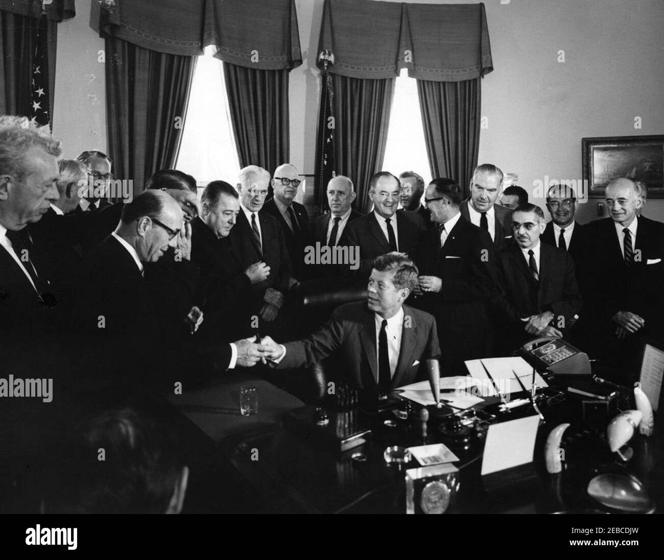 Bill signing, H.R. 11040 Public Law 87-624, Communications Satellite Act of 1962, 9:45AM. President John F. Kennedy hands a pen to Representative Samuel N. Friedel of Maryland during a signing ceremony for HR 11040, the Communications Satellite Act of 1962. (L-R) Senator Everett Dirksen of Illinois; Representative J. Arthur Younger of California (turned away from camera); Representative John B. Bennett of Michigan; Representative Friedel (front, glasses); Representative Oren Harris of Arkansas (mostly hidden behind hand); Senator Warren G. Magnuson of Washington; Speaker of the House of Repres Stock Photo