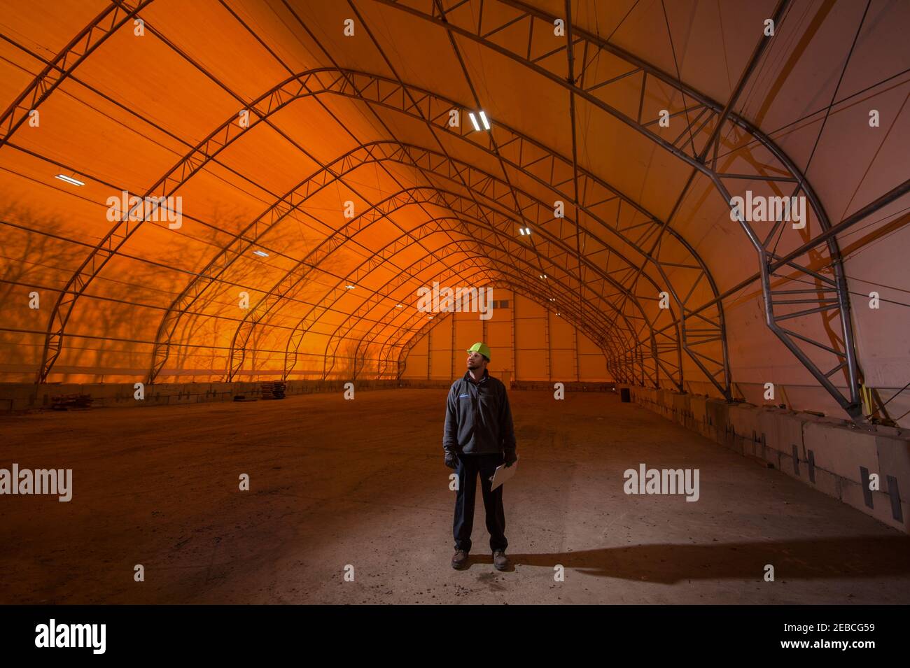 Construction working standing in the middle of an empty temporary warehouse tent, Pennsylvania, USA Stock Photo