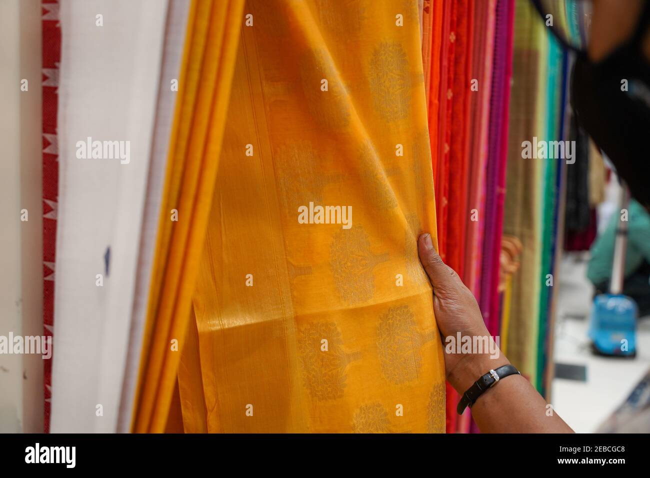 hand of a lady selecting yellow colored saree Stock Photo