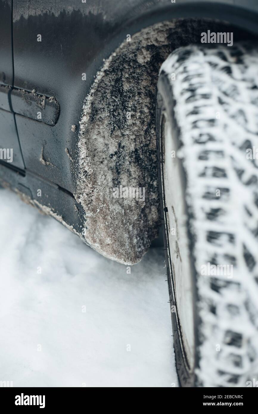 Dirty snow with salt in car wheel arches mud flaps and body
