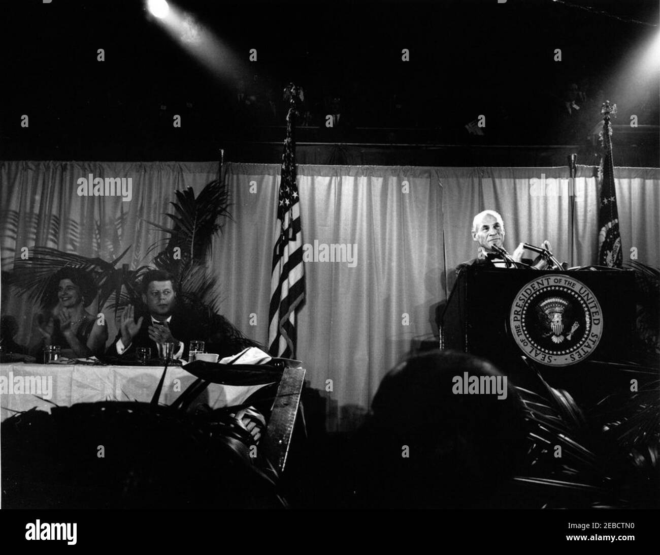 First Inaugural Salute to the President Dinner, Washington, D.C., National Guard Armory, 6:45PM. President John F. Kennedy attends the First Inaugural Salute to the President dinner, commemorating the anniversary of President Kennedyu2019s inauguration. Co-chairman of the dinner and owner of the Baltimore Colts football team, Carroll Rosenbloom, speaks at right; Jane Shields Freeman (co-chairman of the dinner and wife of the Secretary of Agriculture, Orville Freeman) sits at far left. National Guard Armory, Washington, D.C. Stock Photo