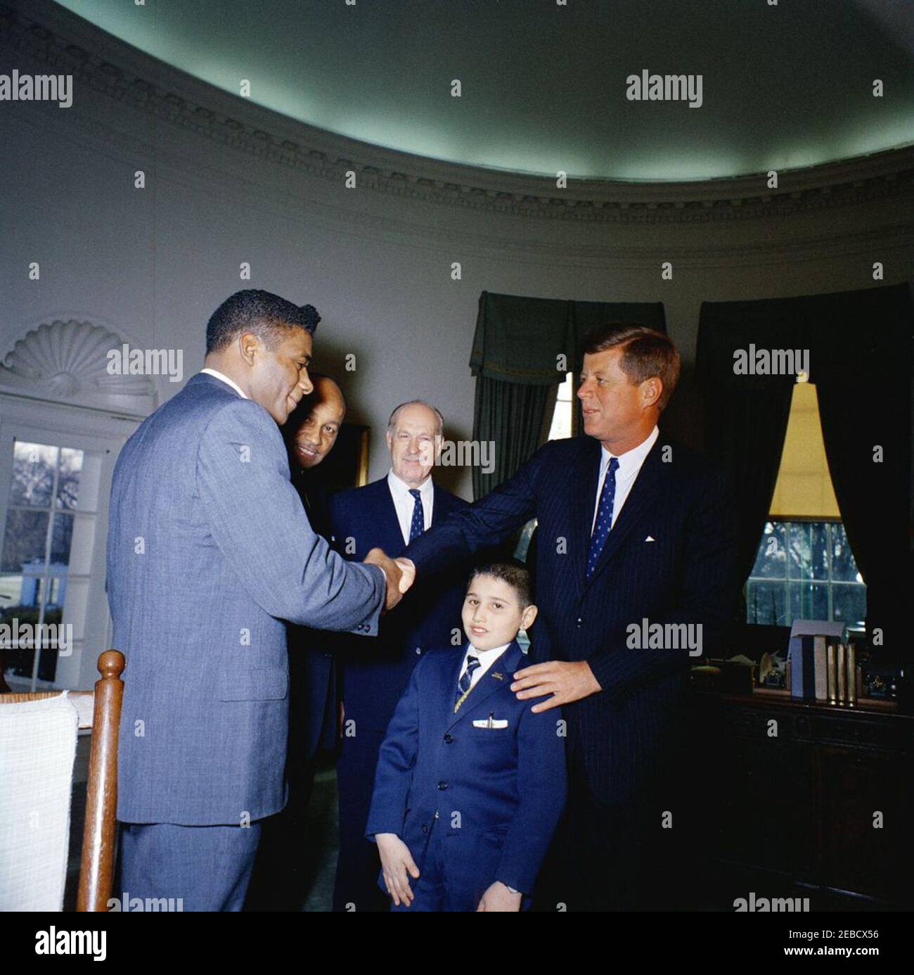 Visit of members of the Big Brothers Association, including Heavyweight Boxing Champion Floyd Patterson, 12:25PM. President John F. Kennedy greets representatives of the Big Brothers Association in connection with Big Brothers Week. The President shakes hands with world heavyweight boxing champion Floyd Patterson, who visited Washington in connection with Big Brothers Week. Looking on are (L-R) John Duncan, member of the District of Columbia Board of Commissioners; journalist Drew Pearson; and ten-year-old Freddie Cicala, a u201clittle brotheru201d member of the Big Brothers organization. Ov Stock Photo