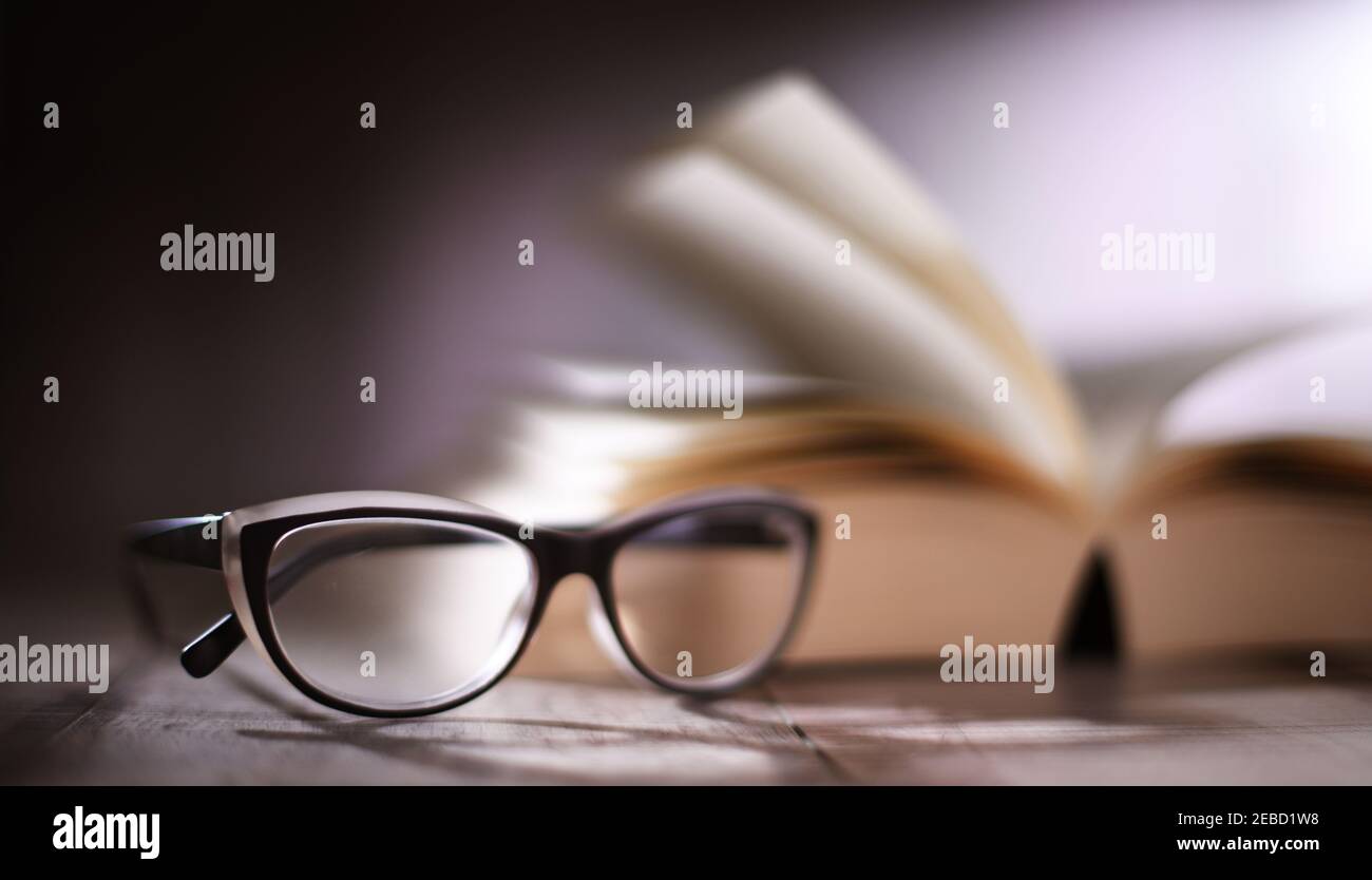 Composition with glasses and open book on the table. Stock Photo