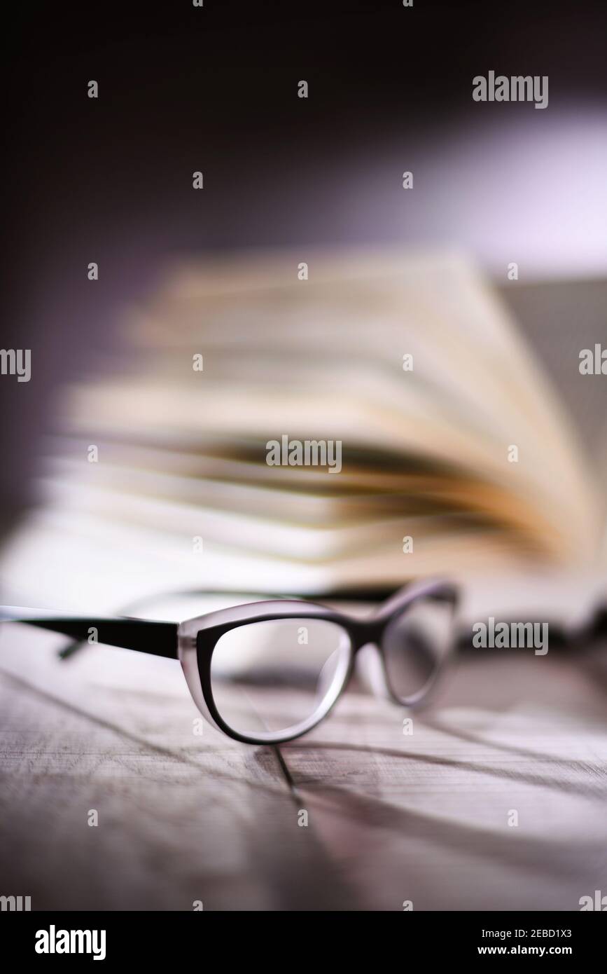 Composition with glasses and open book on the table. Stock Photo