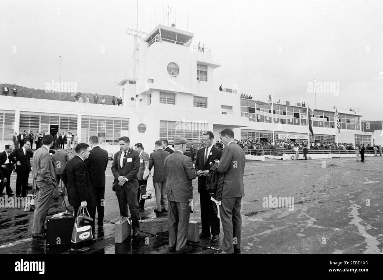 Trip to South America: Caracas, Venezuela, arrival, 9:00AM. Visitors gather at Maiquetu00eda International Airport, Caracas, Venezuela, for President John F. Kennedy and First Lady Jacqueline Kennedyu2019s arrival. White House Army Signal Agency (WHASA) officer, Jack Rubley, stands at right of group speaking to an unidentified man. Stock Photo