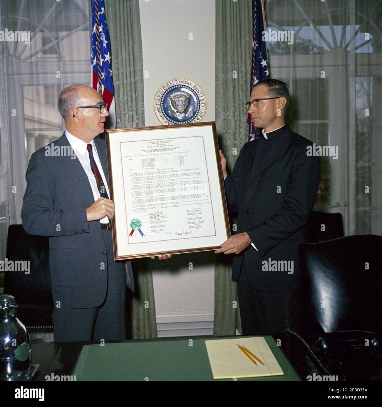 Resolution from the Province of Cotabato, Philippine Islands, presented to the White House. Presidential Assistant Dave Powers (left) accepts a resolution from Kabacan, in the Province of Cotabato, Republic of the Philippines (Philippine Islands); man at right is unidentified. Cabinet Room, White House, Washington, D.C. Stock Photo