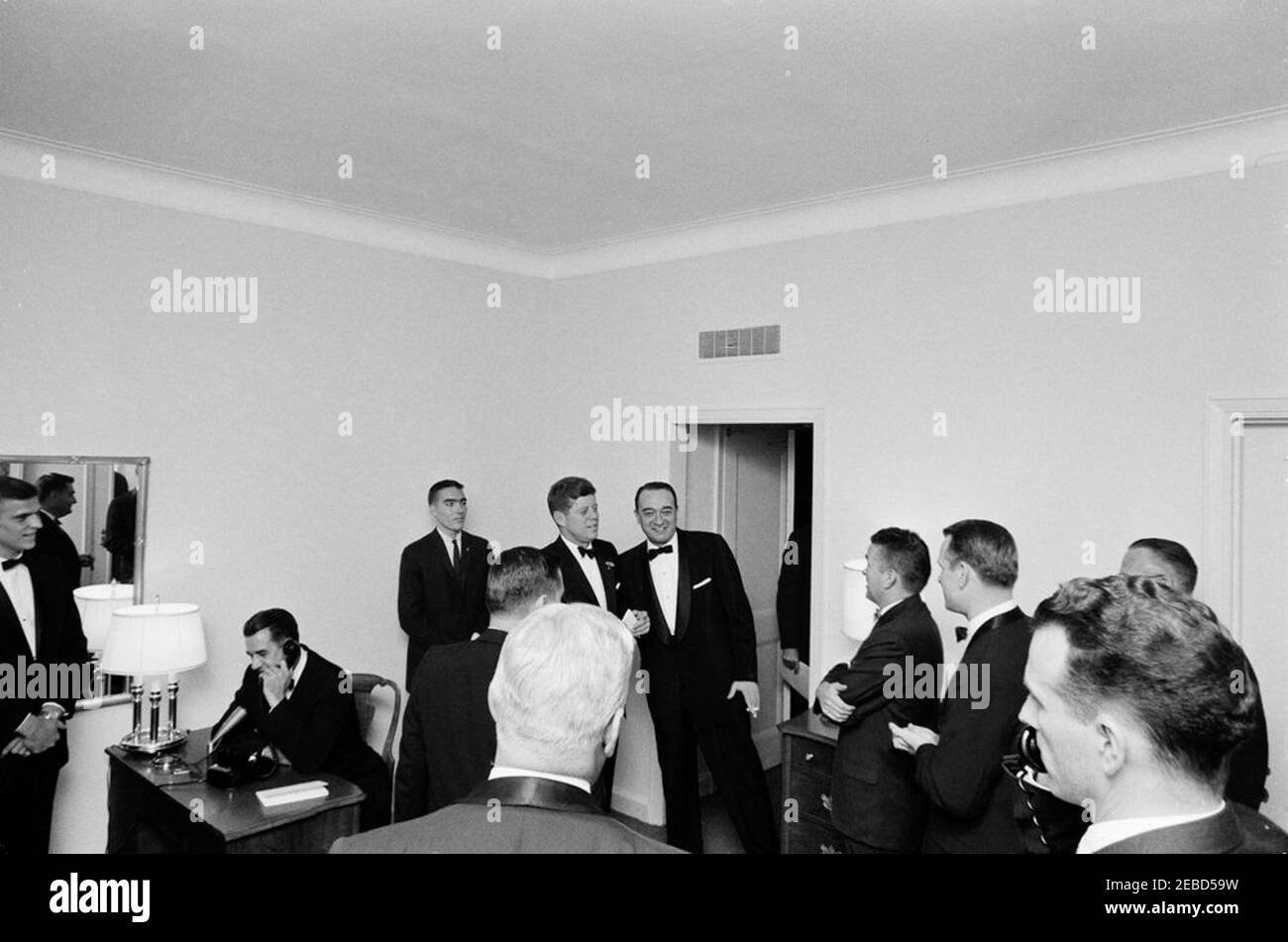 Football Hall of Fame Dinner, New York City, 10:00PM. President John F. Kennedy visits with attendees of the Football Hall of Fame Dinner. L-R: University of Alabama quarterback, Pat Trammell; University of Alabama President, Dr. Frank Rose (speaking on telephone); White House Army Signal Agency (WHASA) staff member, John J. Cochran; Alabama businessman, Tom Russell (in foreground, back to camera); Press Secretary Pierre Salinger (in front of Russell, back to camera); President Kennedy; sportscaster, Mel Allen; Birmingham News sports writer, Benny Marshall; University of Alabama sports Hall of Stock Photo