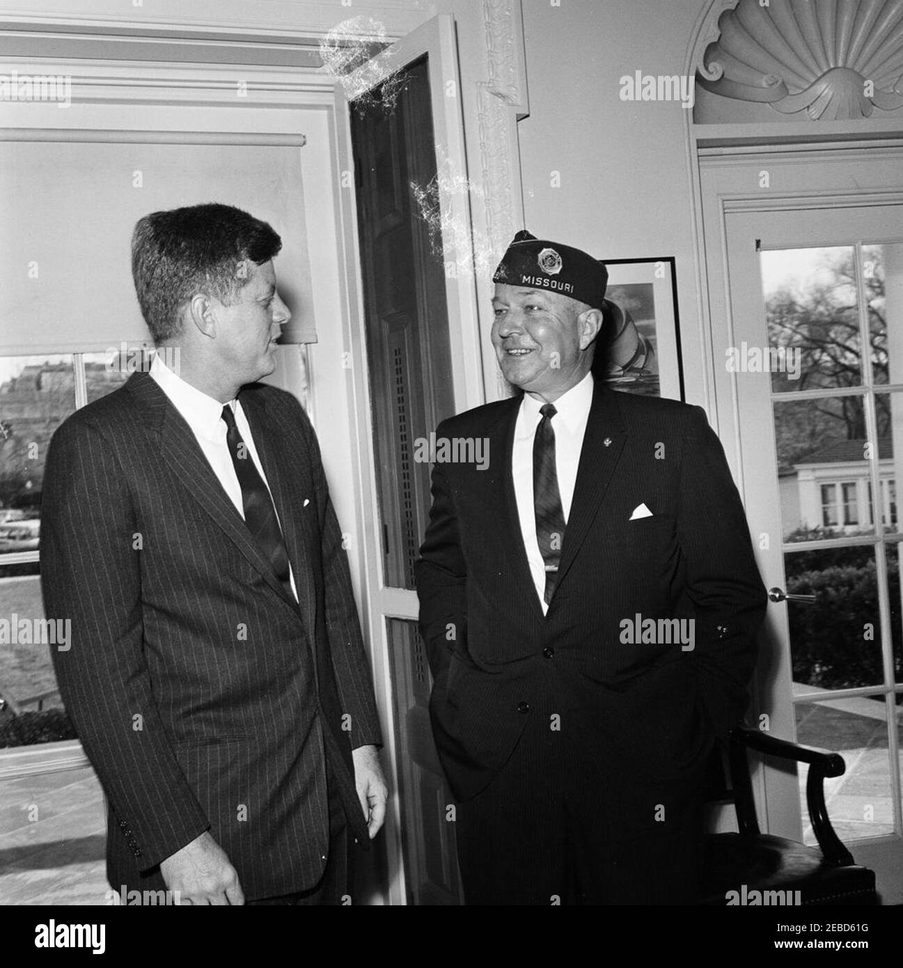 Visit of Charles L. Bacon, National Commander of the American Legion. President John F. Kennedy meets with National Commander of the American Legion, Charles L. Bacon. Oval Office, White House, Washington, D.C. [Blemishes towards top of image are original to the negative] Stock Photo