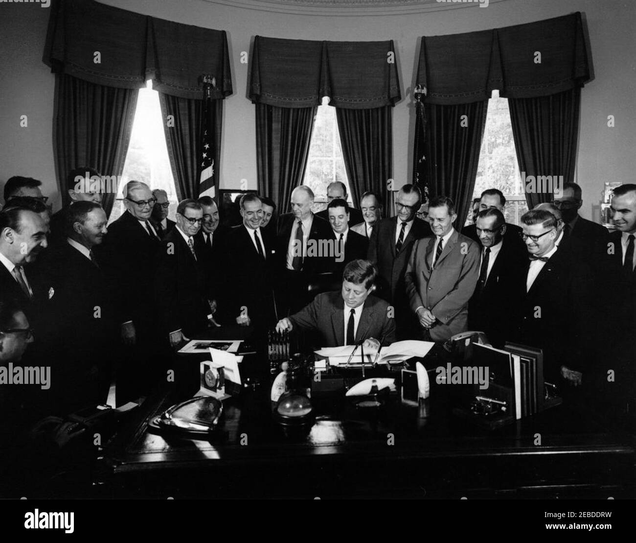 Bill signing - S. 2965 Public Law 87658, Accelerated Public Works Program, 9:30AM. President John F. Kennedy (seated at desk) signs S. 2965, the Public Works Acceleration Act. Looking on (L-R): unidentified stenographer (seated, partially hidden on edge of frame); Secretary of the Department of Health, Education, and Welfare (HEW), Anthony J. Celebrezze; Senator Stephen M. Young (Ohio); Senator Edmund S. Muskie (Maine); Senator Pat McNamara (Michigan); Senator John Sherman Cooper of Kentucky (in back); Senator Dennis Chu00e1vez (New Mexico); Senator Jennings Randolph (West Virginia); Represen Stock Photo