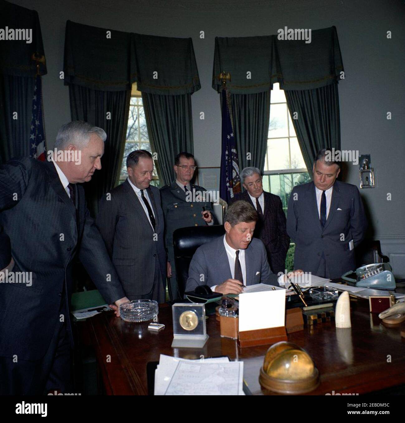 President Kennedy signs emergency flood relief measures for Kentucky counties, 11:30AM. President John F. Kennedy (seated at desk) signs emergency flood relief measures for Kentucky counties in the Oval Office of the White House, Washington, D.C. Standing (L-R): Congressman Carl D. Perkins (Kentucky); Congressman John C. Watts (Kentucky); Adjutant General of Kentucky, A. Y. Lloyd; Administrative Assistant to Congressman Watts, Paul Kelly; Governor of Kentucky, Bert T. Combs. Stock Photo