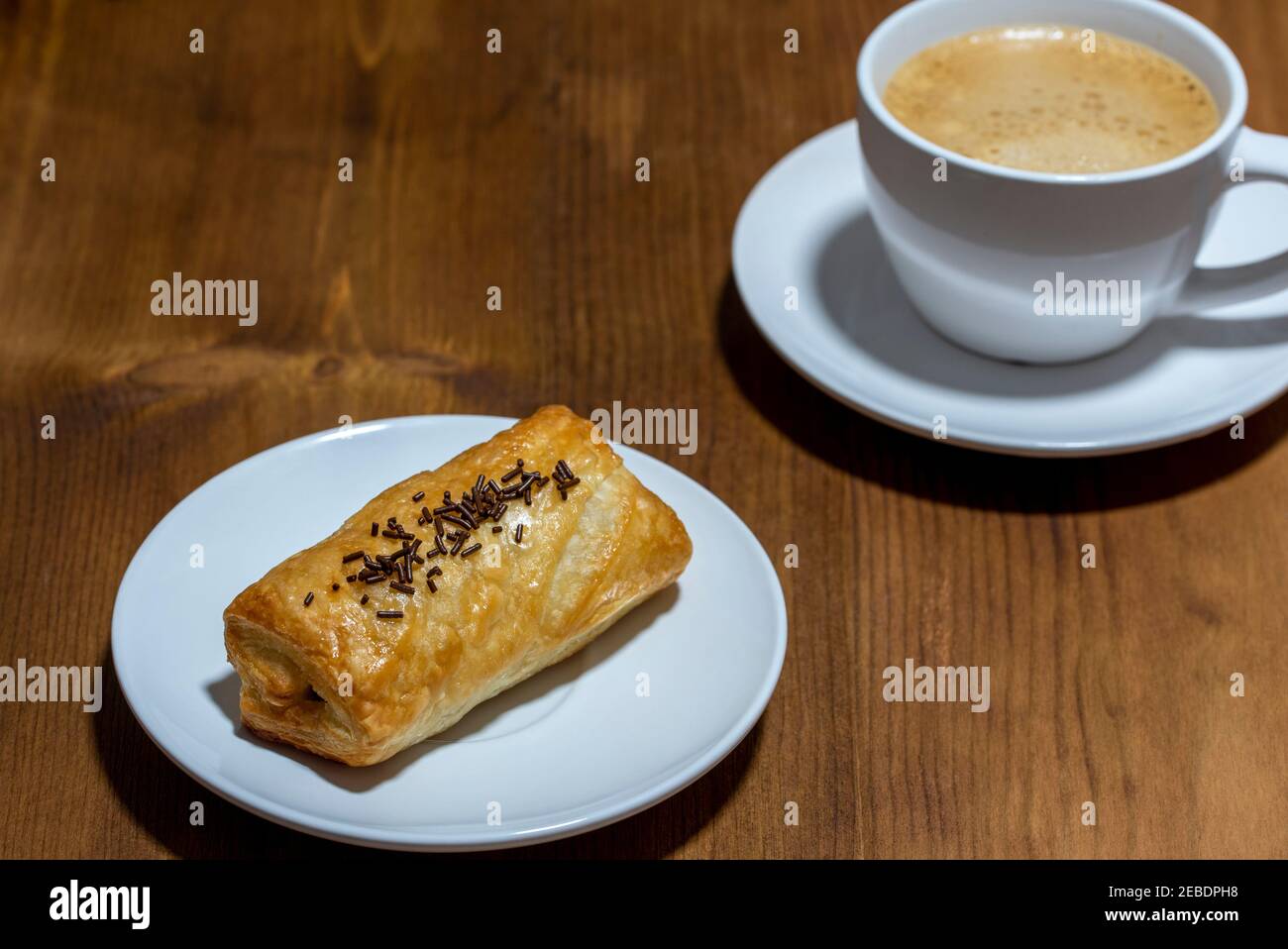 pain au chocolat and cup coffee on a wooden dark background Stock Photo