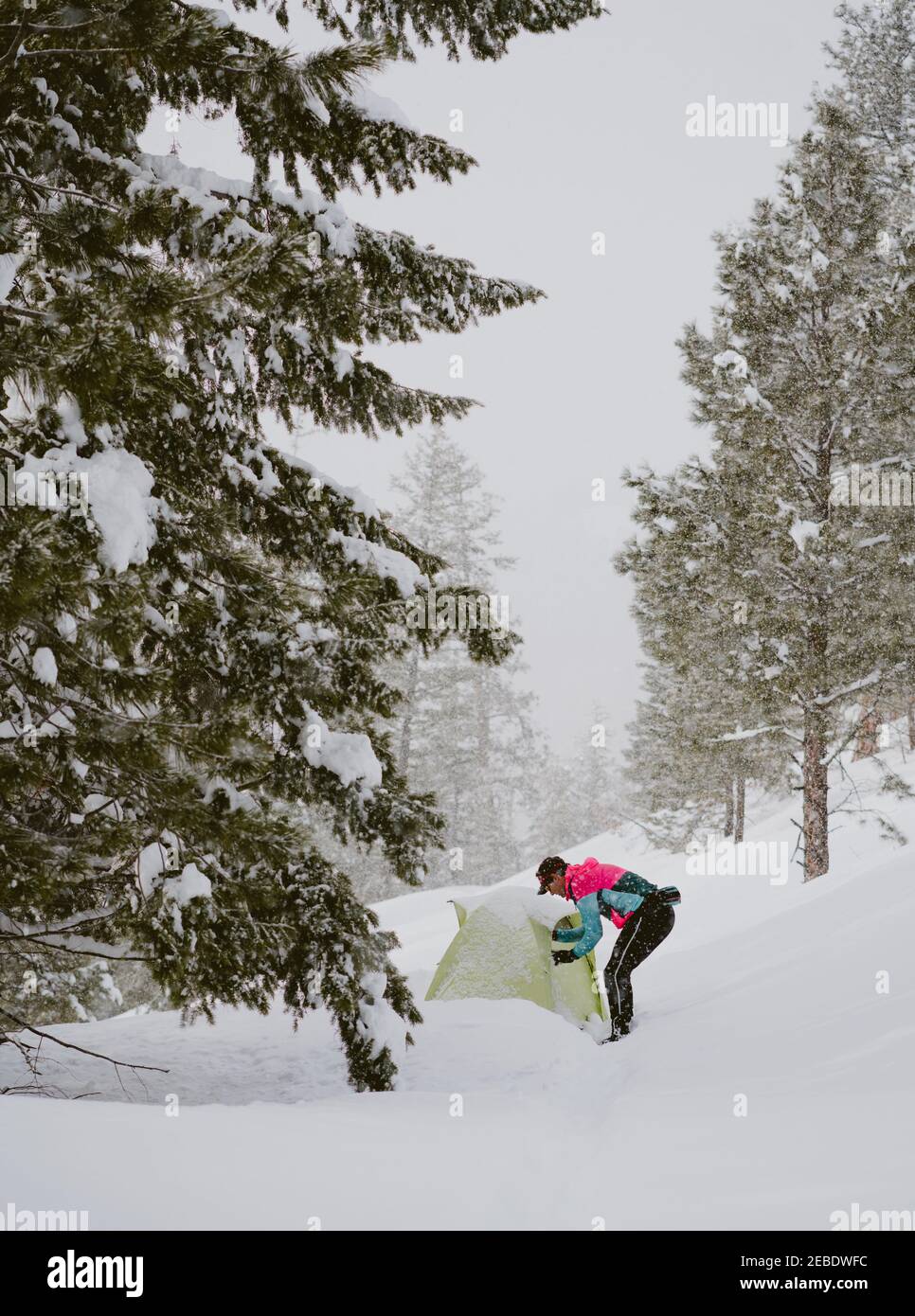 A man in bright jacket stands outside tent in deep snow Stock Photo