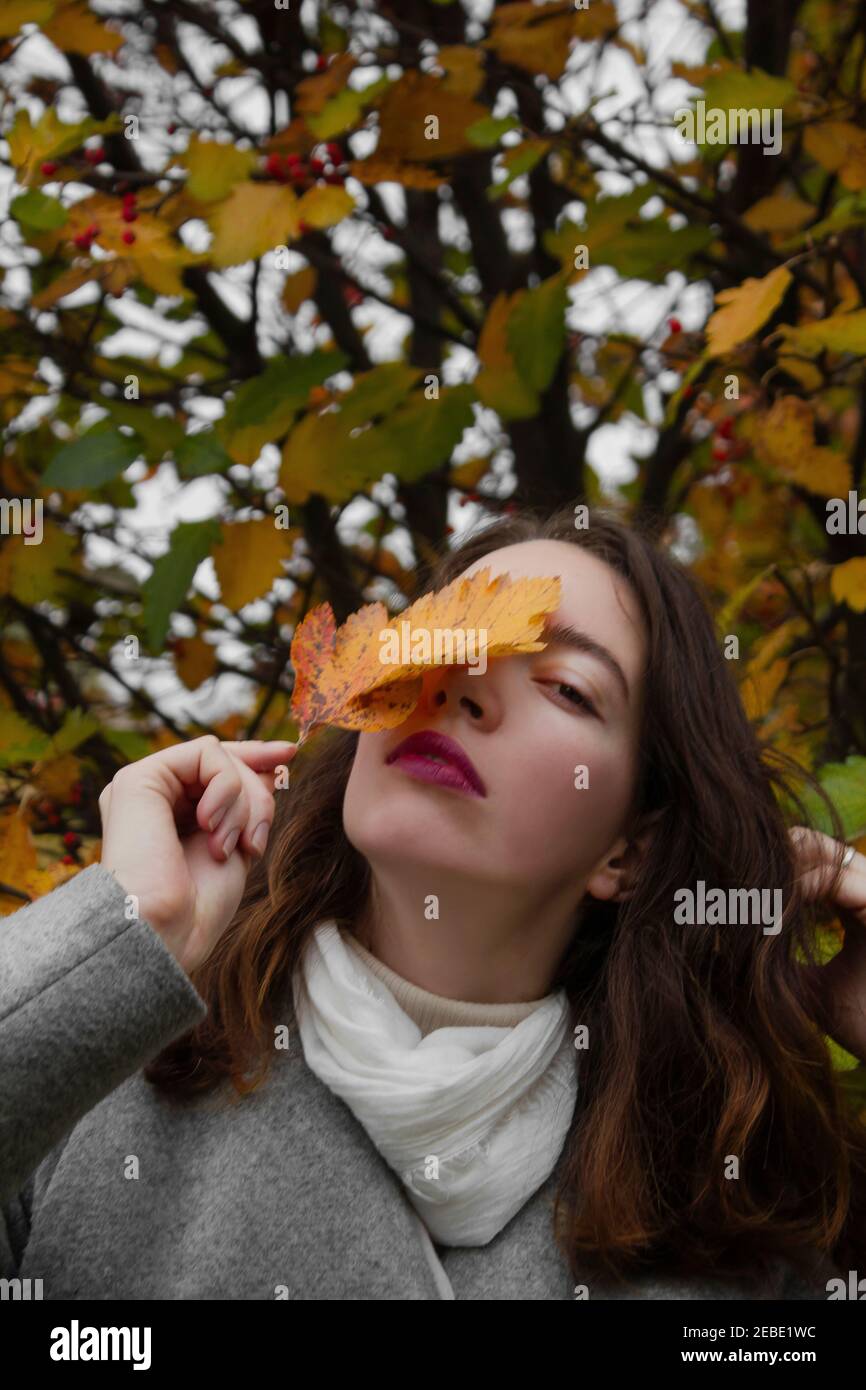 Girl holding yellow leaf near face Stock Photo - Alamy