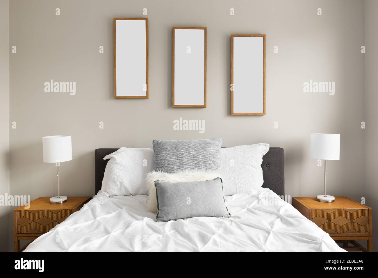 https://c8.alamy.com/comp/2EBE3A8/detail-shot-of-a-cozy-bedroom-with-white-bedding-and-grey-pillows-pictures-of-leaves-above-the-bed-and-lamps-on-wooden-nightstands-2EBE3A8.jpg