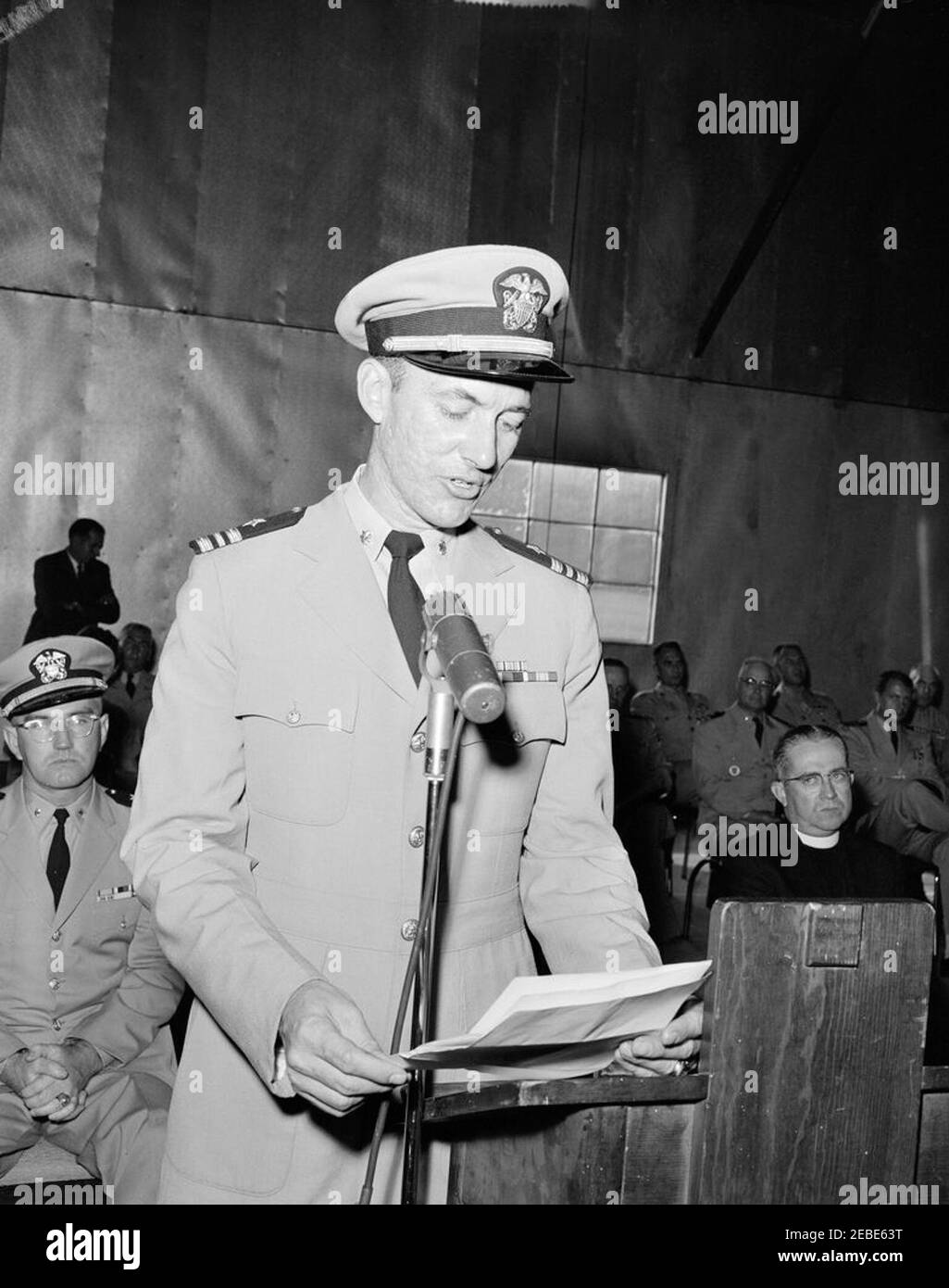 Camp David, Change of Command Ceremony (no President Kennedy). Unidentified officer of the United States Navy speaks before a group of military and civilian observers during a ceremony marking a change of command of the Presidentu2019s retreat at Camp David. Naval Aide to the President Captain Tazewell T. Shepard sits at right in background. Camp David, Frederick County, Maryland. [Photograph by O.W. Harris] Stock Photo