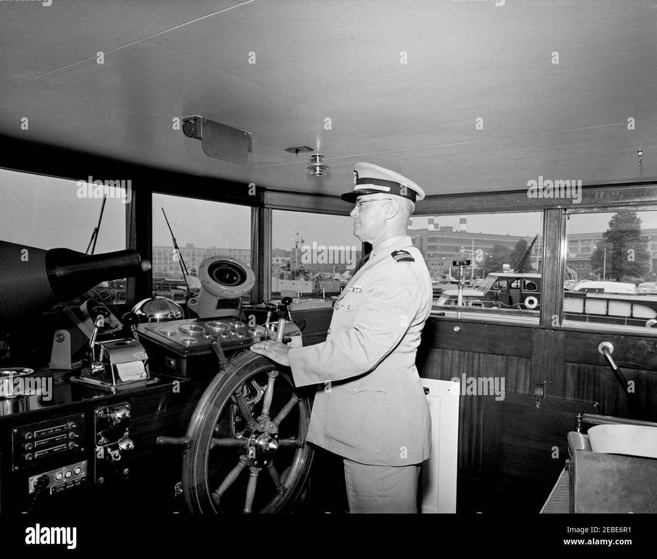Yacht Honey Fitz berthed at Washington Navy Yard, interior and exterior views. Lieutenant Commander Walter C. Slye stands at the helm in the pilothouse of the Presidential yacht u0022Honey Fitzu0022 at the Washington Navy Yard, Washington, D.C. Stock Photo