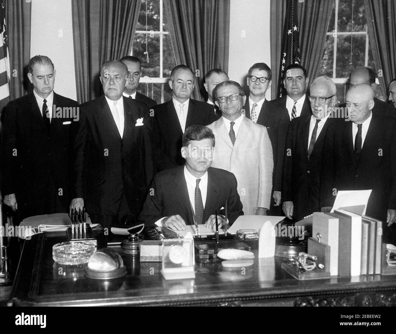 Bill signing, S. 1643 Public Law 87-128, Agricultural Act of 1961, 9:45 AM. President John F. Kennedy speaks during the signing ceremony for S. 1643, the Agricultural Act of 1961. The bill was legislated to improve farm income, expand the market for agricultural products, and reduce stocks of grains and wheat. Standing behind President Kennedy are (L-R): Senator Olin Johnston of South Carolina; Representative Harold D. Cooley of North Carolina; Vice President Lyndon B. Johnson; Senator Hubert Humphrey of Minnesota; Representative W.R. Poage of Texas (mostly hidden); Senator Allen Ellender of L Stock Photo