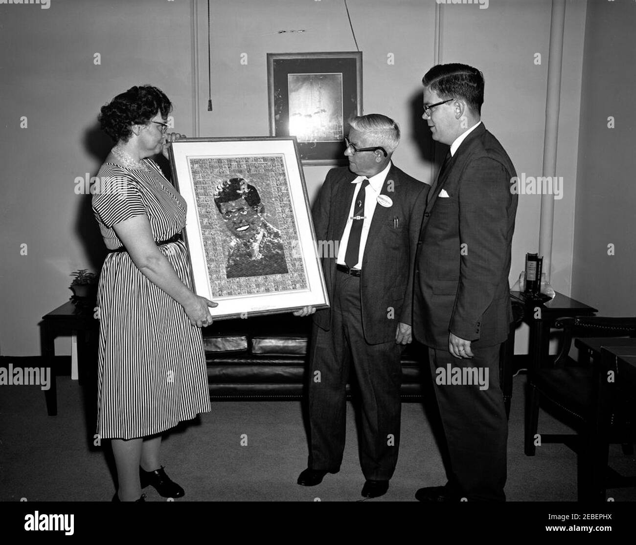 Mr. and Mrs. Jacob Blackburn of Baltimore, Maryland present a portrait of President Kennedy to Presidential Assistant John J. McNally. Dora and Jacob Blackburn of Baltimore, Maryland present a portrait of President John F. Kennedy made of ribbon and postage stamps to Presidential Assistant John J. u201cJacku201d McNally (far right). East Wing, White House, Washington, D.C. [The portrait is currently located at the John F. Kennedy Presidential Library and Museum as MO 63.292] Stock Photo