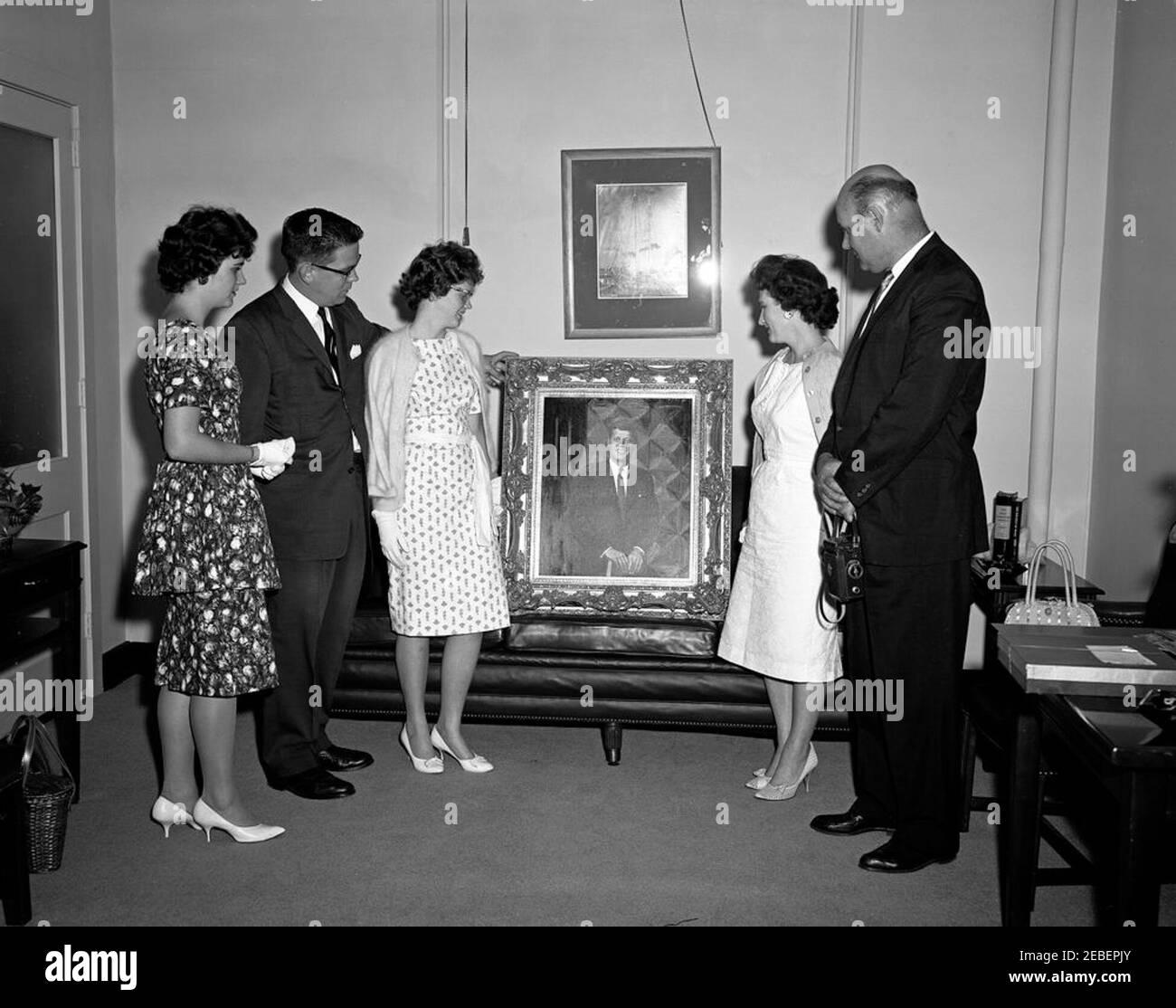 Bernard Benson family presents a portrait of President Kennedy to Presidential Assistant John J. McNally. Bernard Benson, his wife Helen, and two daughters, Pat and Barbara, present a portrait of President John F. Kennedy to Presidential Assistant John J. u201cJacku201d McNally (standing at left between the Benson daughters). East Wing, White House, Washington, D.C. Stock Photo