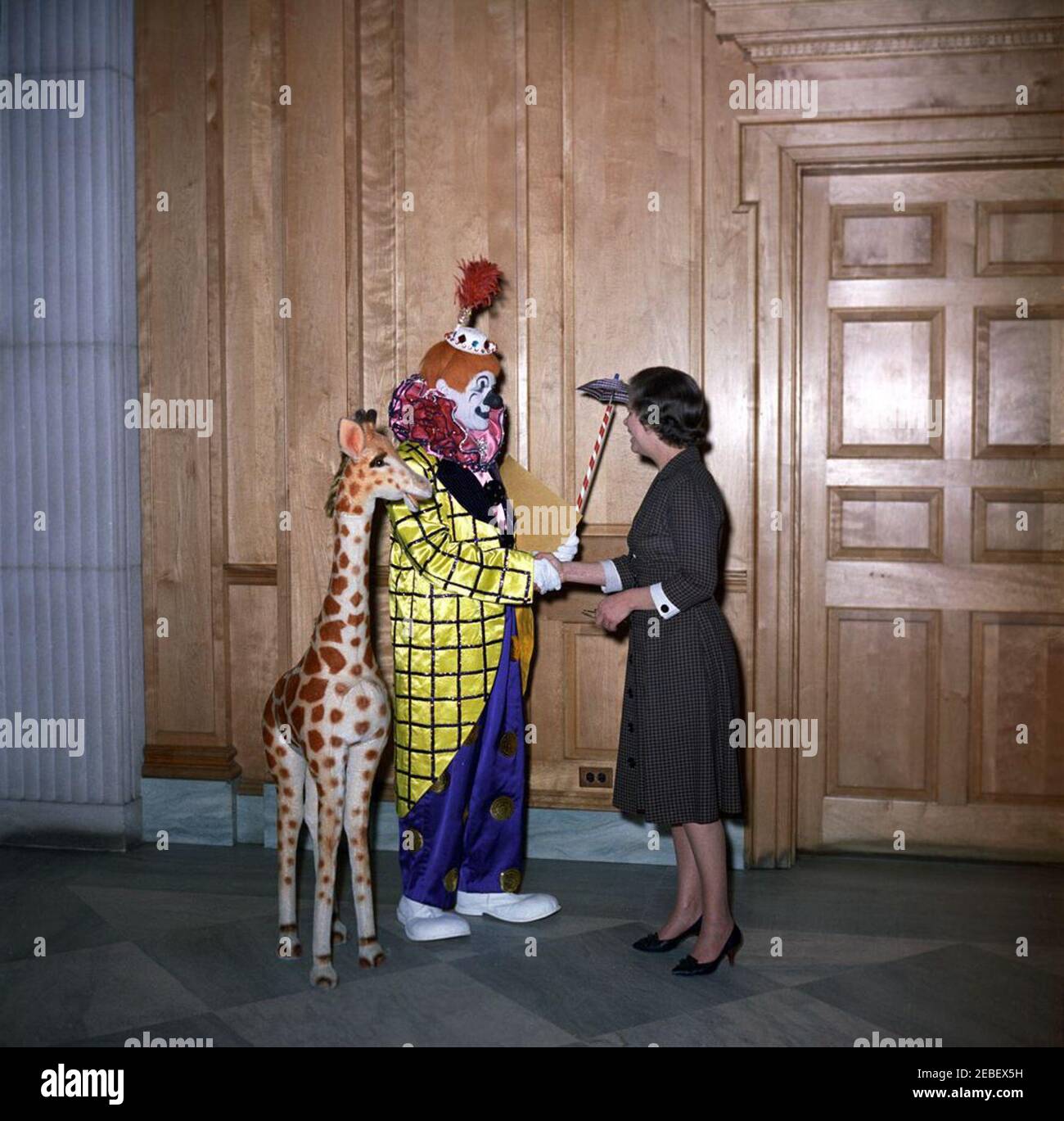 Ringling Bros. and Barnum u0026 Bailey Circus clown Jackie Le Claire presents a gift for Caroline Kennedy (CBK), with David Polland and Hortense Burton (John J. McNally). Hortense Burton, Chief of the Correspondence Pool in the Social Entertainments Office, greets Ringling Bros. and Barnum u0026 Bailey Circus clown, Jackie LeClaire, who is presenting a toy stuffed giraffe as a gift for Caroline Kennedy. East Wing Lobby, White House, Washington, D.C. Stock Photo