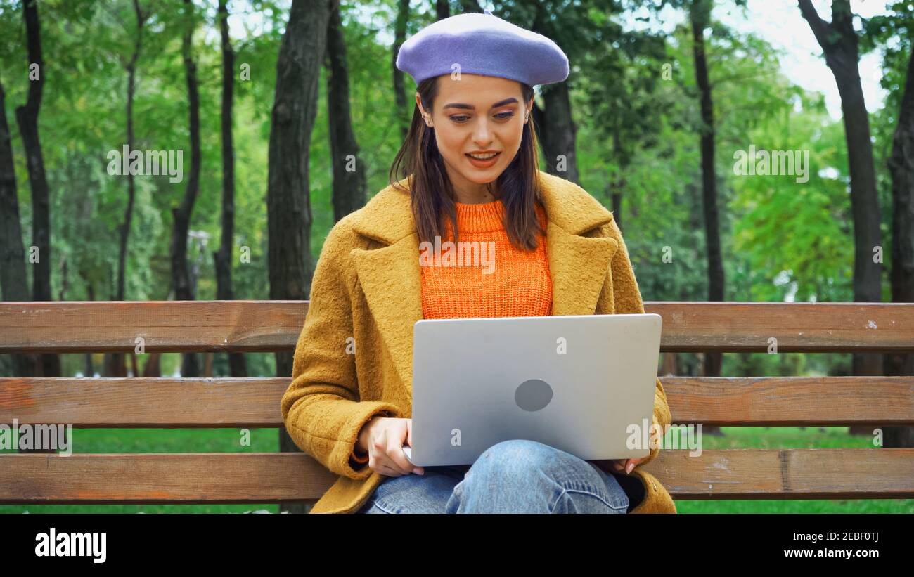 smiling freelancer working on laptop in autumn park Stock Photo